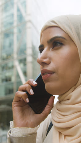 Vertikales-Video-Einer-Muslimischen-Geschäftsfrau-Mit-Mobiltelefon,-Die-Vor-Dem-Büro-In-Stadt-1-Steht